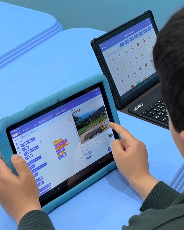 RoboStars student building an interactive story with block-based coding on a tablet