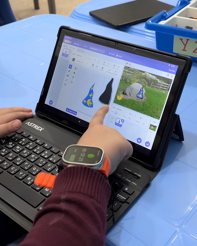 RoboStars student animating a Scratch character over a custom garden backdrop