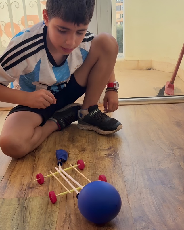 RoboStars student testing a balloon-powered car build on the floor